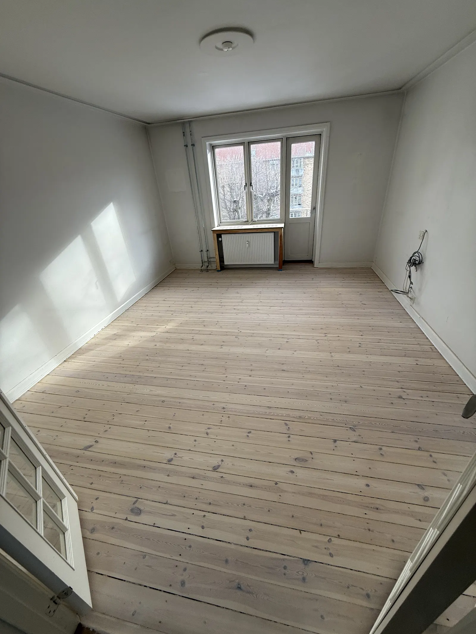 Lyst, nyslebet plankegulv i en tom lejlighed